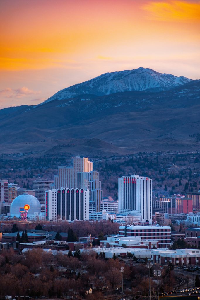 Downtown Reno casinos at sunset with mountains in the distance